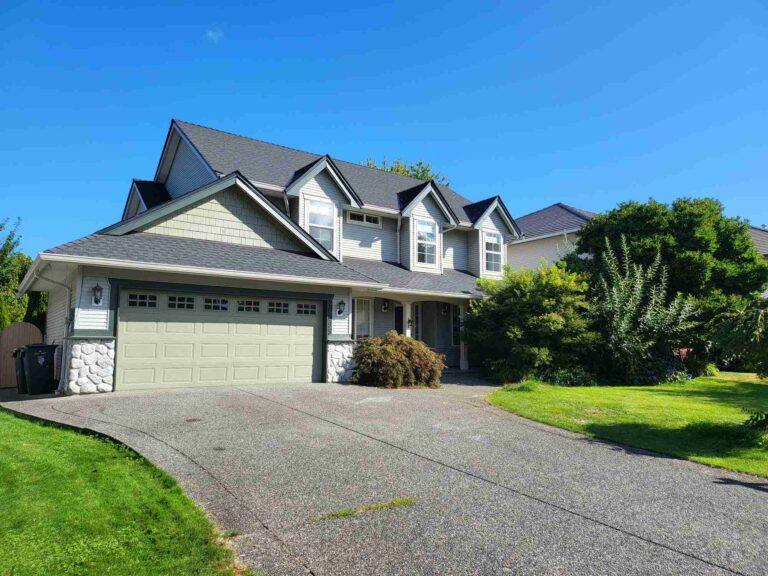 An untouched backyard at 91B Ave Langley with overgrown grass and basic landscaping before the renovation.