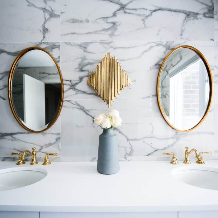 Chic bathroom vanity with marble backdrop, dual round mirrors, and gold accents.