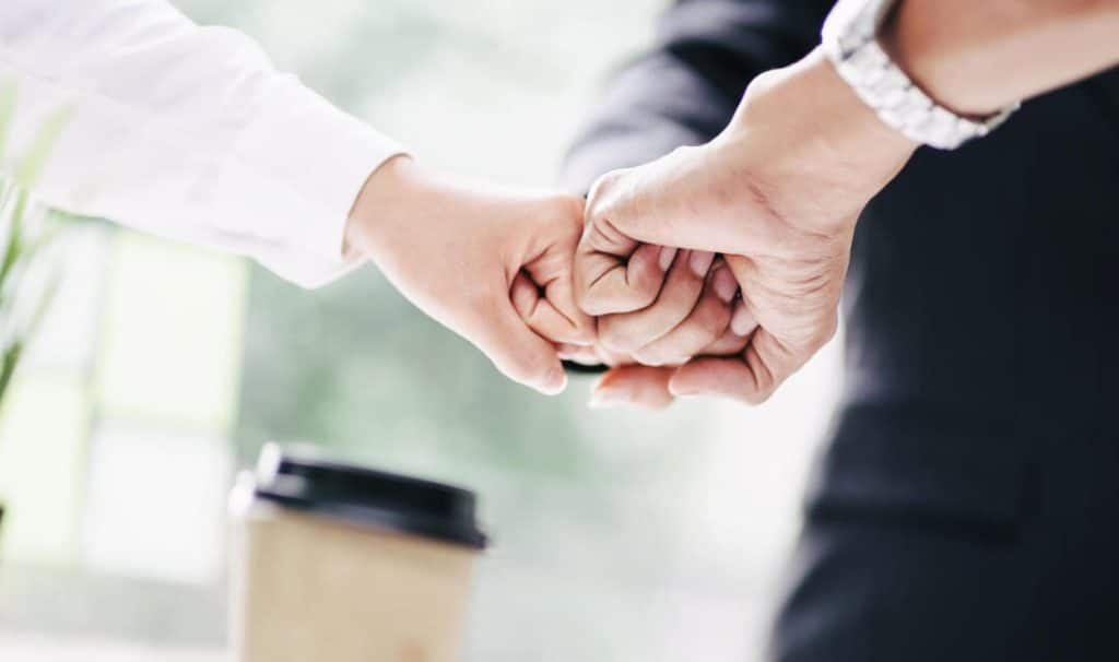 Close-up of a team fist bump in a corporate setting.