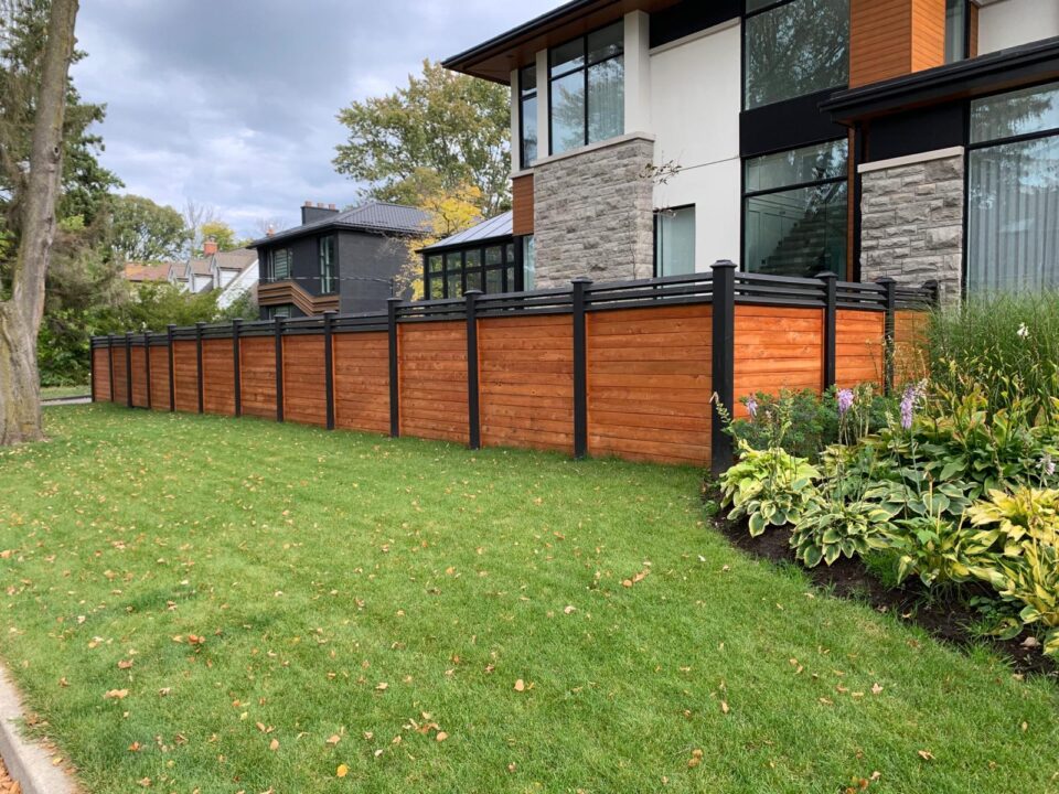 A modern wood-and-black exterior fence enhancing curb appeal for a well-prepared, market-ready home.