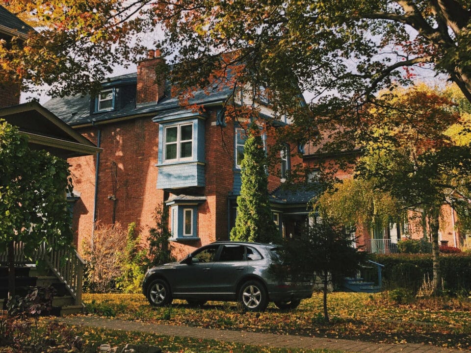 Brick century home with autumn leaves across the front lawn