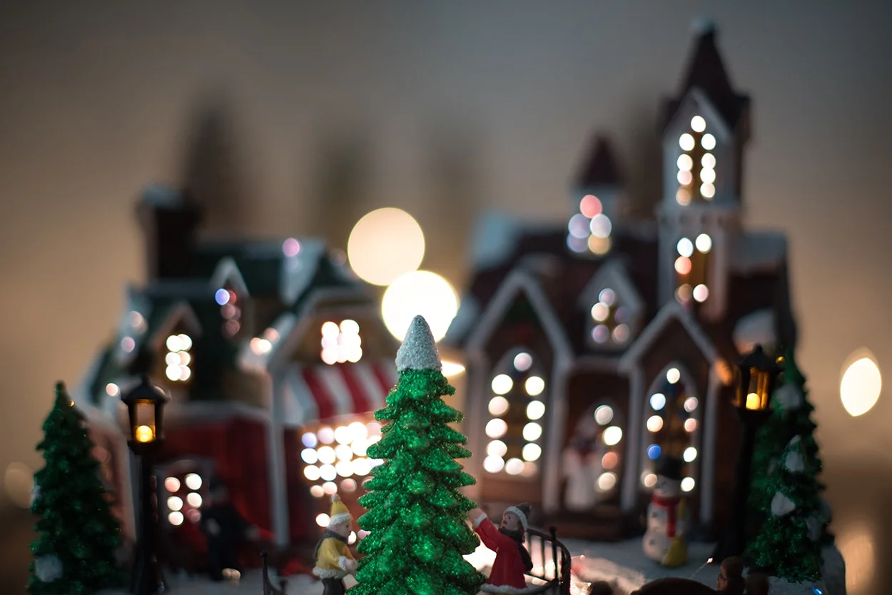 Miniature lit Christmas village scene with snow and a decorated tree