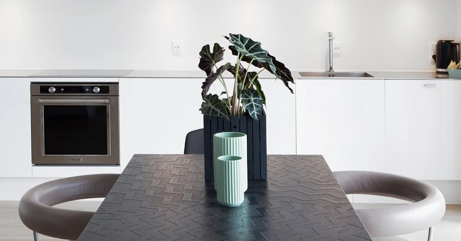 Minimalist white kitchen with a dark textured dining table and mint vases