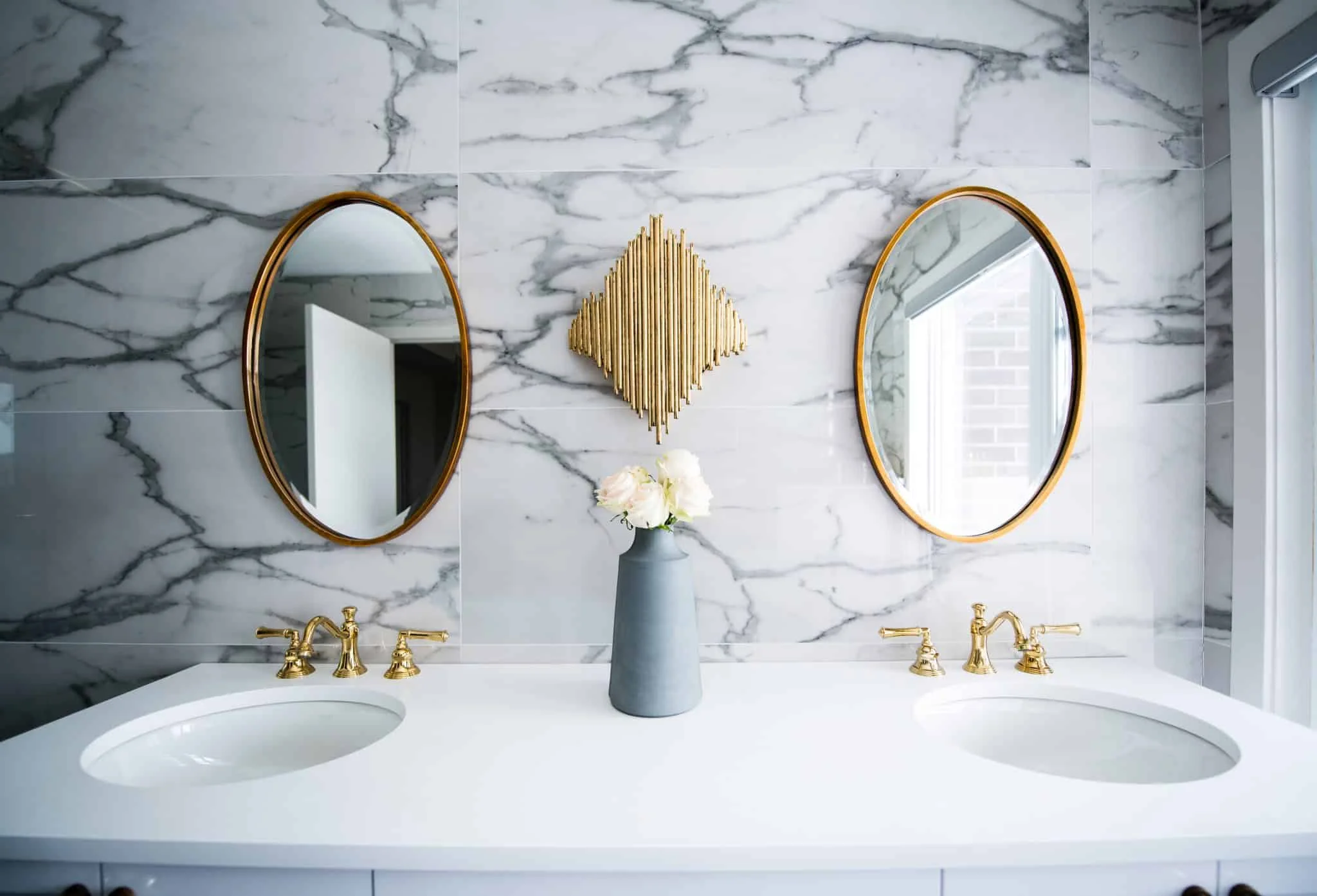 Chic bathroom vanity with marble backdrop, dual round mirrors and gold accents