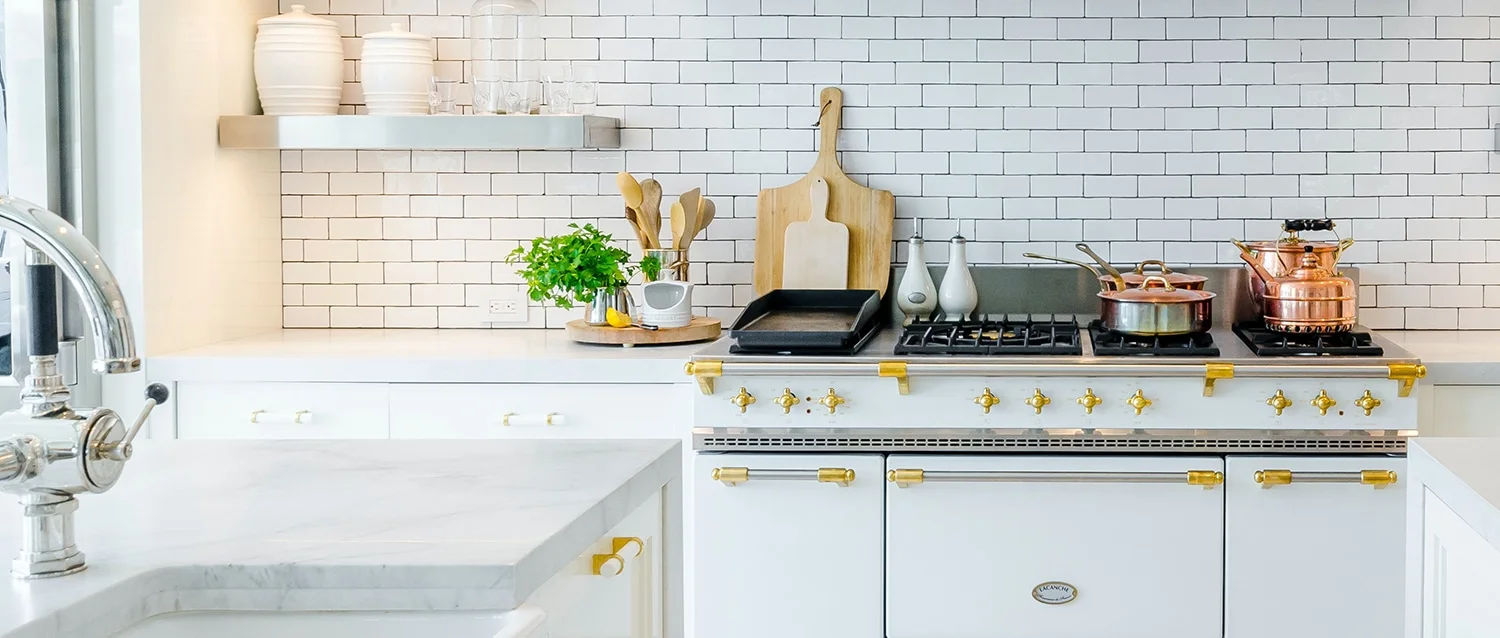 Sleek kitchen showcasing white marble countertops and a classic stove with brass accents